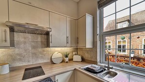 Eine moderne Küche mit einem großen Fenster, einem eingebauten Ofen und Blick auf ein Backsteingebäude.