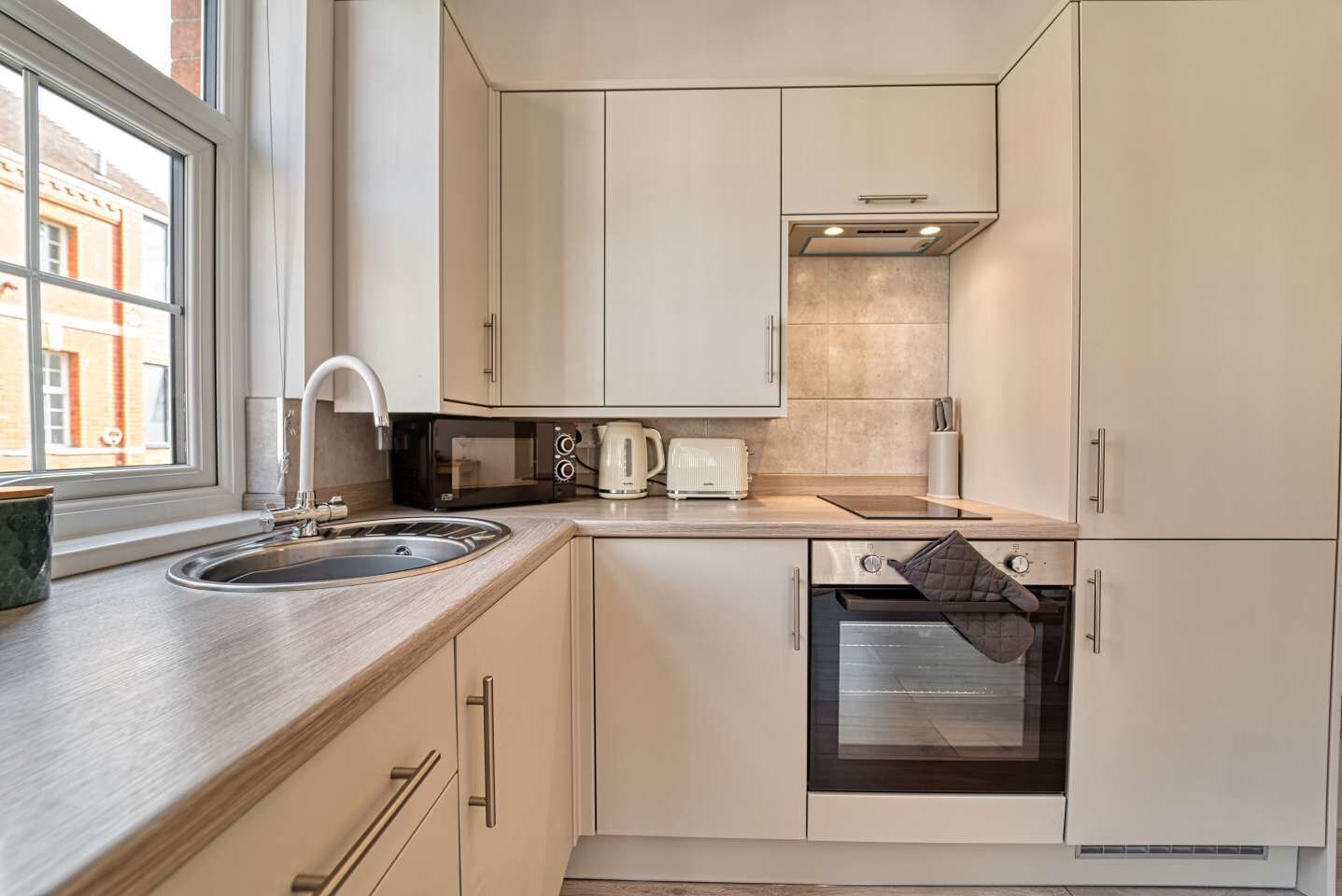A compact kitchen with a sink, a microwave, a kettle, and an oven.
