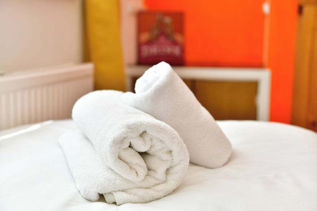 A neatly made bed with white towels and a pillow.
