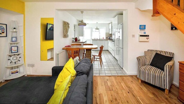 Uma sala de estar moderna com um sofá, uma poltrona listrada e um espaço de jantar com mesa e cadeiras.
