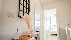 Ein Flur mit einer Holzbank, einer Vase mit Pampasgras und einem an der Wand montierten Lichtschalter.