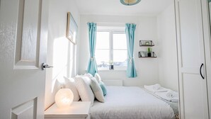 Ein Schlafzimmer mit Bett, Nachttisch und einem Fenster mit Vorhängen.