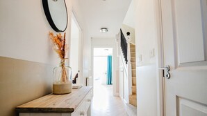 Ein Flur mit einem Holztresen, einer Vase mit Trockenblumen, einem Spiegel und einer Treppe, die in einen anderen Raum führt.