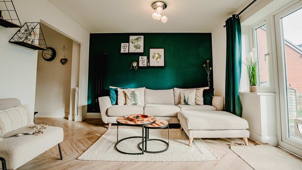 Ein modernes Wohnzimmer mit grüner Akzentwand, einer Sofagarnitur, einem Couchtisch und einer Treppe.