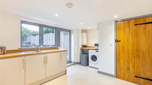 A modern kitchen with a built-in washing machine, a large window, and a wooden door. - Host Stay Bridge Street Residence (Leominster)
