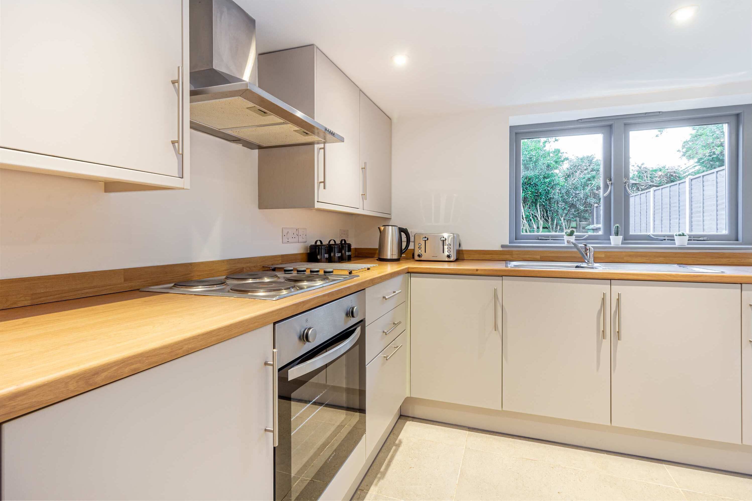 Una cocina moderna con encimera de madera, electrodomésticos de acero inoxidable y armarios blancos.