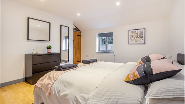 A bedroom with a bed, bedside tables, a dresser, a window, and framed artwork on the walls. - Host Stay Bridge Street Residence (Leominster)