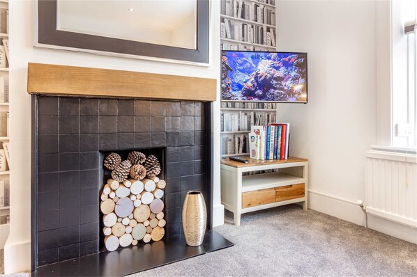 Una sala de estar con chimenea, una estantería y un televisor.