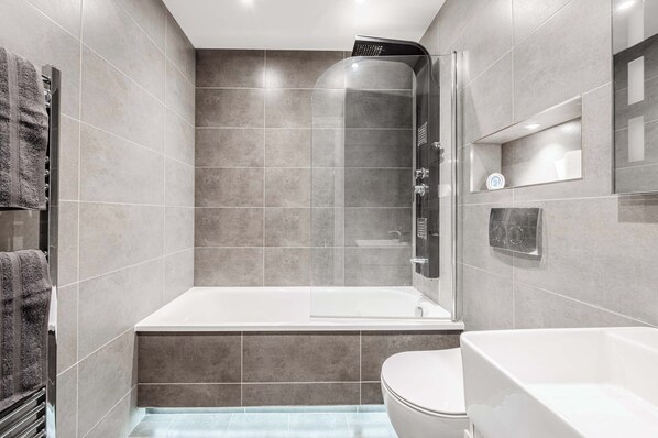Une salle de bain moderne avec une douche à parois de verre, une baignoire blanche et des toilettes.