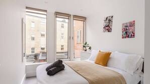 Ein Schlafzimmer mit einem Bett, einem Fenster und zwei Bildern an der Wand.