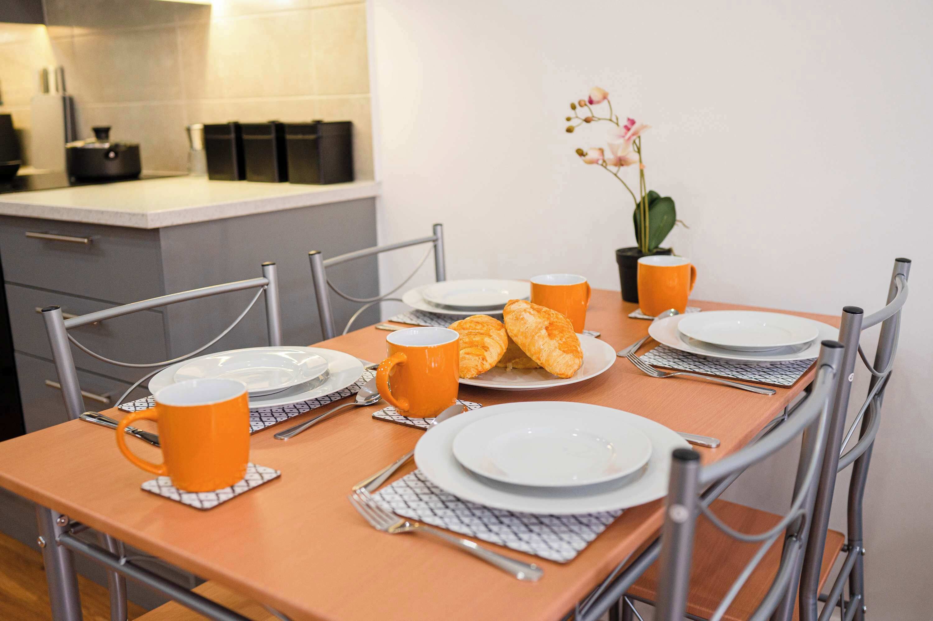 A dining table set with plates, a mug, and a pastry.