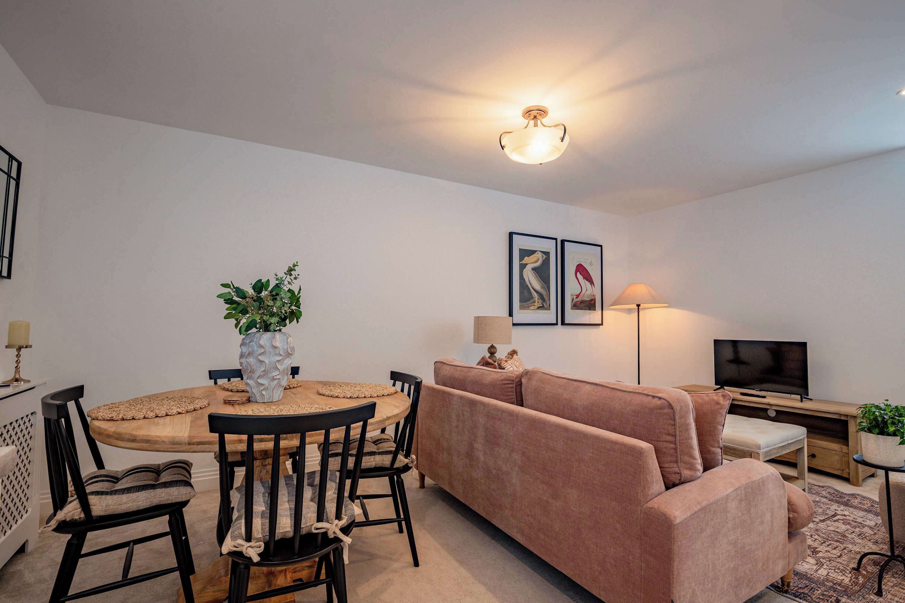 A modern living room with a round dining table, a sofa, a TV, and a lamp.