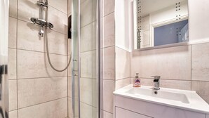 A modern bathroom with a glass shower enclosure, a white sink with a soap dispenser, and a mirror above the sink. - Host Stay Lion Court (Worcester)