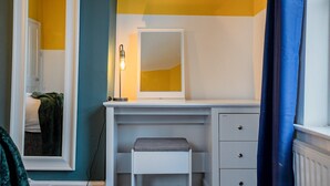 Un bagno con un mobile lavabo bianco, uno specchio e una panca.