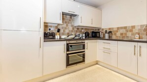 A modern kitchen with white cabinets, a double oven, a microwave, and a tiled backsplash. - Host Stay Hillbrook House Apartment (Malvern)
