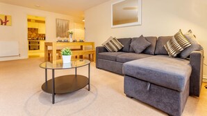 A modern living room with a grey sofa, a glass coffee table, and a wooden dining table. - Host Stay Hillbrook House Apartment (Malvern)
