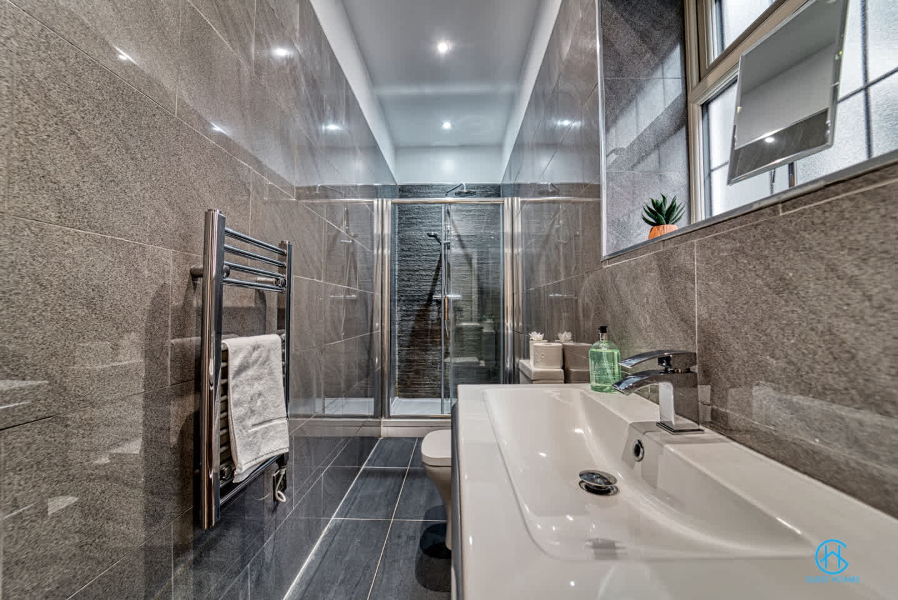 A modern bathroom with a glass-enclosed shower, a large bathtub, and a toilet.