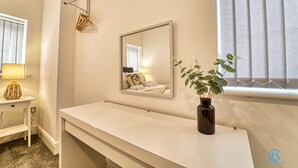 A bathroom with a white vanity, a mirror, a plant, and a window with blinds. - Host Stay The Bell (Stourbridge)