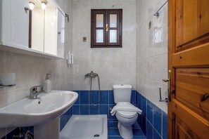 Une salle de bain avec un lavabo blanc, une douche et des toilettes.