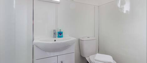 A modern bathroom with a white sink, toilet, and cabinets.