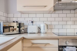 Une cuisine moderne avec des appareils électroménagers blancs, un plan de travail et un revêtement mural en carreaux.