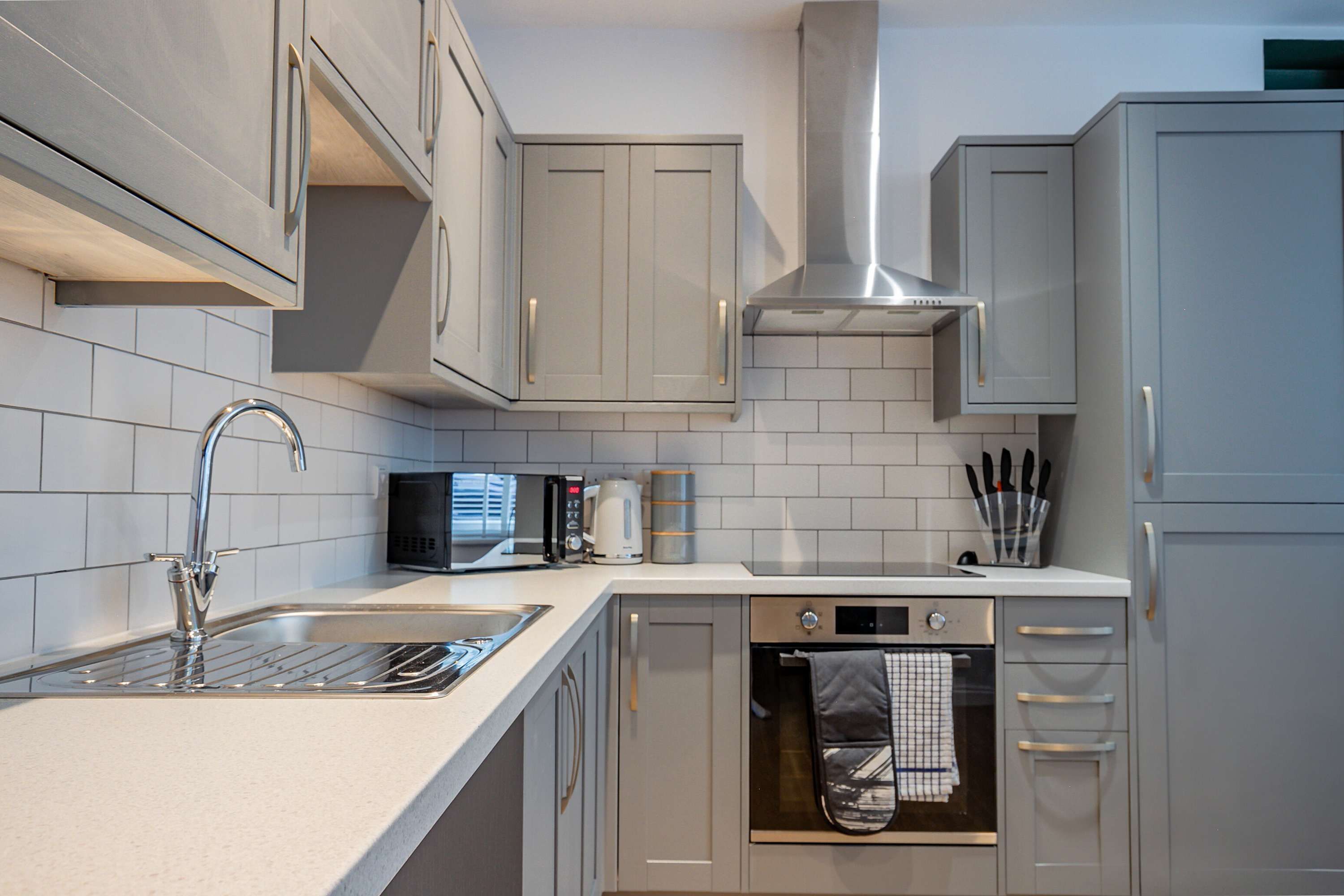 A modern kitchen with white cabinets, a stainless steel sink, a microwave, and a dishwasher.