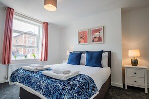 A hotel room with a large bed, a nightstand, a lamp, and two framed pictures on the wall. - Host Stay Bromyard Flat 1 (Worcester)