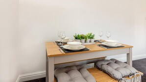 Une table à manger dressée avec des assiettes, des verres et une petite plante.