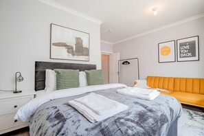 A modern bedroom with a large bed, a nightstand, a bedside table, a floor lamp, and a sofa. - Host Stay Bridge Street Apartment (Evesham)