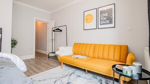 A modern living room with a yellow sofa, a small side table, and a framed motivational quote on the wall. - Host Stay Bridge Street Apartment (Evesham)
