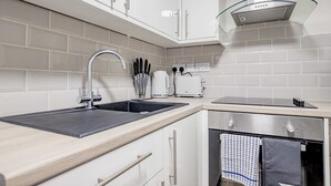 A modern kitchen with white cabinets, a stainless steel range hood, a double sink, and a built-in oven. - Host Stay Bridge Street Apartment (Evesham)