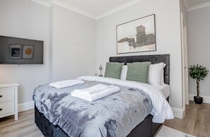 A modern bedroom with a large bed, a flat-screen TV, and a painting on the wall. - Host Stay Bridge Street Apartment (Evesham)