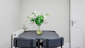 A dining table with a vase of white flowers, two chairs, and a white door in the background. - Host Stay Bridge Street Apartment (Evesham)
