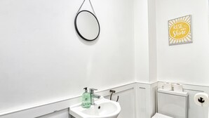 Un bagno moderno con lavandino, wc e specchio bianchi.