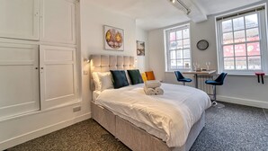 Una camera d'albergo moderna con un letto grande, una scrivania con due sedie, una finestra vista città e un armadio.