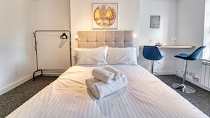 Ein Hotelzimmer mit einem Bett, einem Schreibtisch, zwei Stühlen und einem Kleiderhaken.