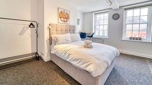 A bedroom with a bed, a radiator, a window with a view, and a clock on the wall.