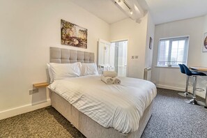 Una habitación de hotel moderna con una cama grande, un escritorio y una silla.