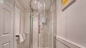 Une douche fermée par des parois de verre, avec un mur en marbre, un porte-serviettes et un sèche-mains.