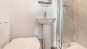 A bathroom with a toilet, sink, and glass shower enclosure. - Host Stay The Bull Inn Flat 1 (Worcester)