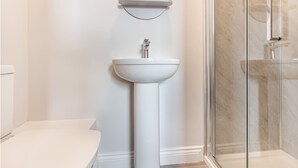 A bathroom with a white pedestal sink, a mirror above it, and a glass shower enclosure. - Host Stay The Bull Inn Flat 2 (Worcester)