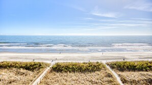 A beach with a wooden boardwalk, sandy shore, and ocean view. - Waterpointe II 705 | Oceanfront 3 Bedroom Condo (North Myrtle Beach)