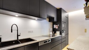 A modern kitchen with dark cabinets, a granite countertop, and built-in appliances. - Chic Apt With Garden - 1bd/2p - Neuilly-sur-seine (Neuilly-sur-Seine)
