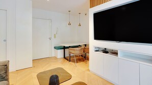 A modern living room with a flat-screen TV, a dining area with a table and chairs, and a sofa. - Chic Apt With Garden - 1bd/2p - Neuilly-sur-seine (Neuilly-sur-Seine)