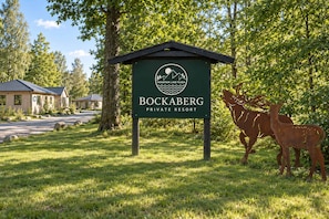 Segnaletica per Bockberg Private Resort, con logo, grafica di montagna e lago e due sculture di cervi.