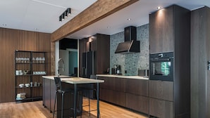 Een moderne keuken met donker houten kastjes, een centraal eiland met barstoelen en ingebouwde apparatuur.