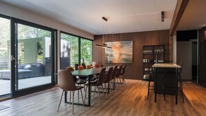 Een moderne eethoek met een grote tafel, stoelen en een bar.