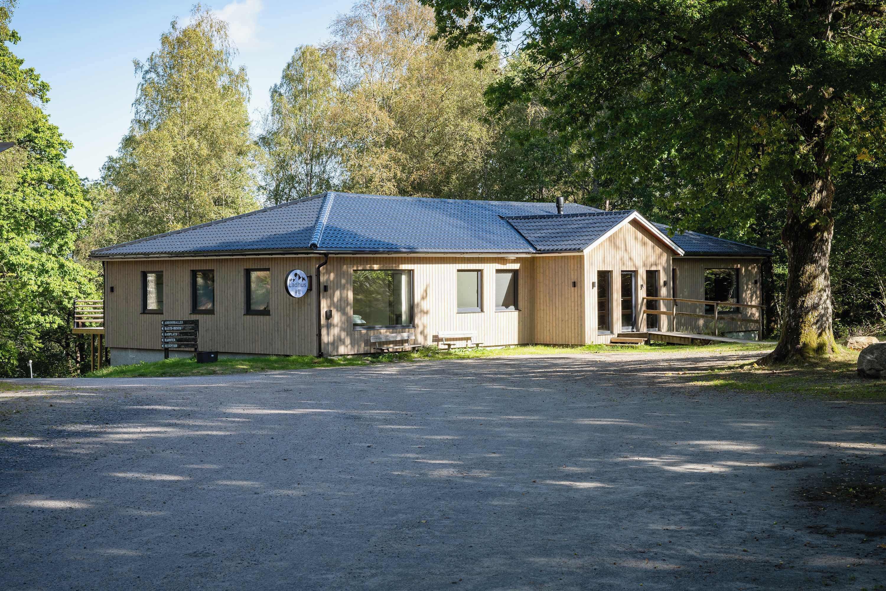 En byggnad av trä med ett blått tak, en veranda och en skylt som visar vilka bekvämligheter som finns.