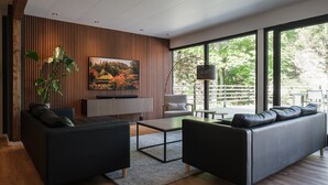 Een moderne woonkamer met een groot raam, een flatscreen televisie en een bank.
