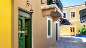 Une ruelle étroite, avec un immeuble jaune sur la gauche et un immeuble beige sur la droite.